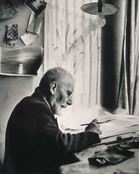 Aimé Prelle dessinant à sa table de travail, photographie noir et blanc